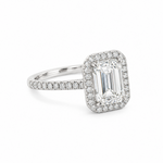 An emerald-cut halo ring featuring a large clear center stone surrounded by a halo and a pavé-set band, shown on a clean white background.