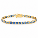 A yellow gold tennis bracelet featuring a row of emerald-cut sapphires, displayed on a clean white background.