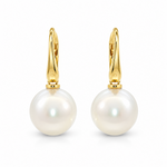A pair of gold huggie hoop earrings with large, lustrous white South Sea pearls hanging from gold posts, shown on a clean white background.