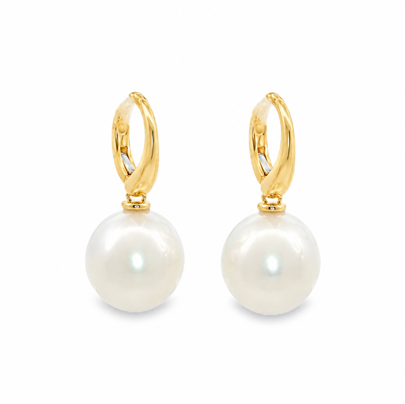 A pair of gold huggie hoop earrings with large, lustrous white South Sea pearls hanging from gold posts, shown on a clean white background.