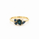 18ct yellow gold ring featuring a random cluster of Australian blue sapphires in pear, round, and marquise cuts with diamond accents and a post and bezel undercarriage.