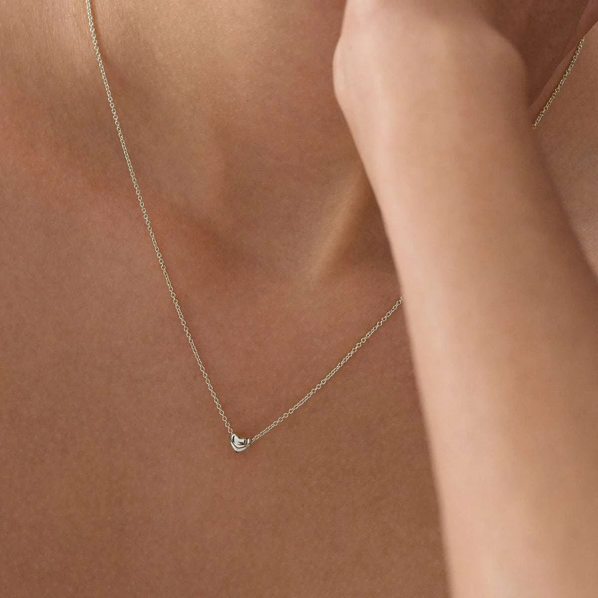 Sterling silver puff heart necklet worn on the neckline.