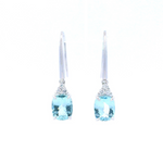 18ct white gold aquamarine and diamond drop earrings featuring cushion cut aquamarines suspended from triangular diamond clusters with articulated hook fittings.
