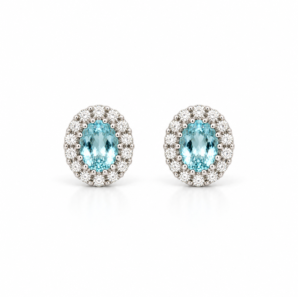 18ct white gold aquamarine and diamond halo stud earrings featuring oval-cut blue aquamarines surrounded by round brilliant cut diamonds.