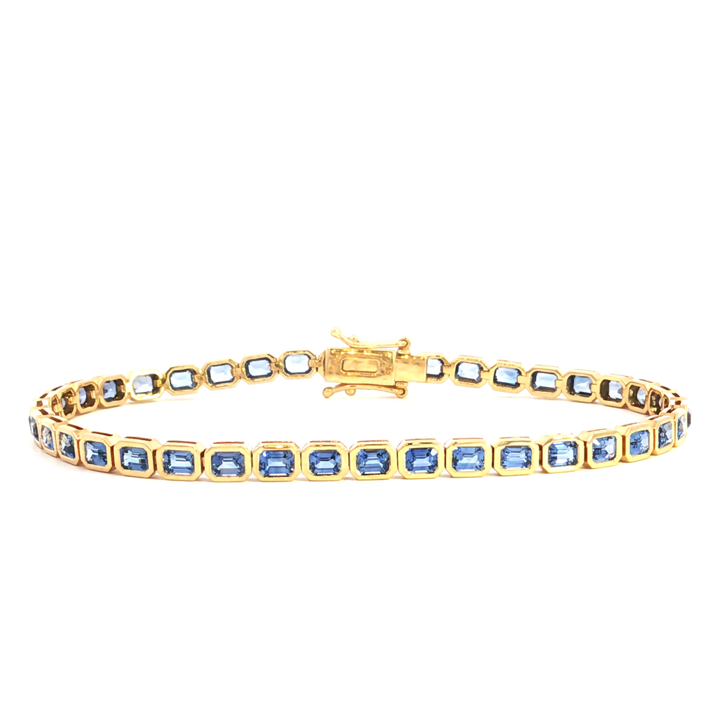 18ct yellow gold blue sapphire bracelet featuring articulated octagonal links with bezel-set emerald cut sapphires.