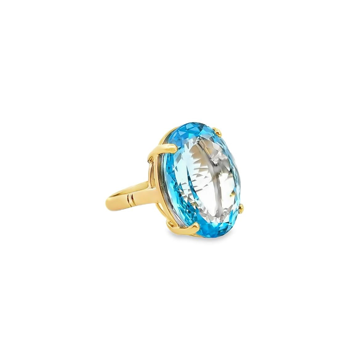 9ct yellow gold ring featuring a 23.90 x 18.60mm oval cut blue topaz in a four-claw setting with engraved shoulders.