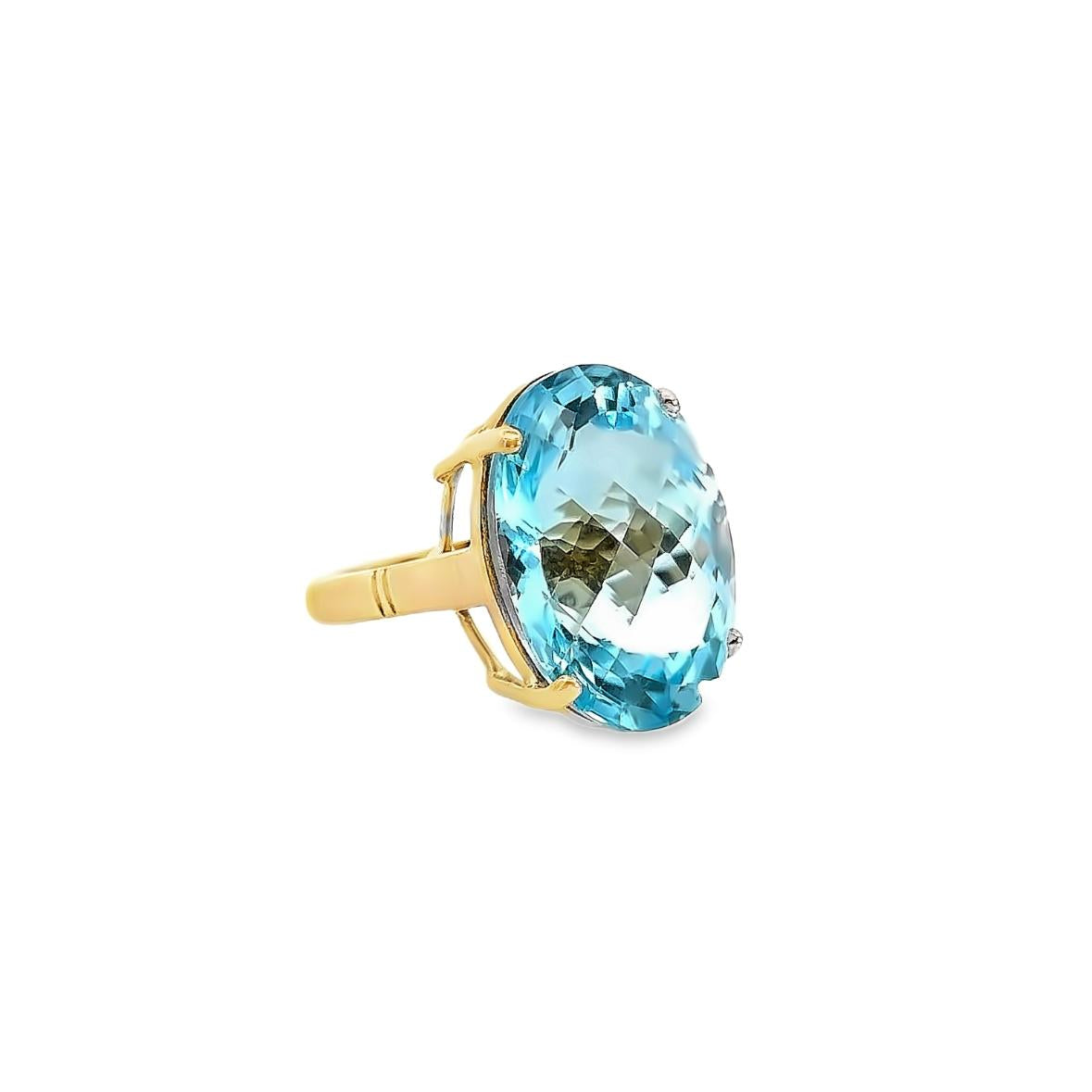 9ct yellow gold ring featuring a 23.70 x 17.75mm oval cut blue topaz in a four-claw setting with engraved shoulders.