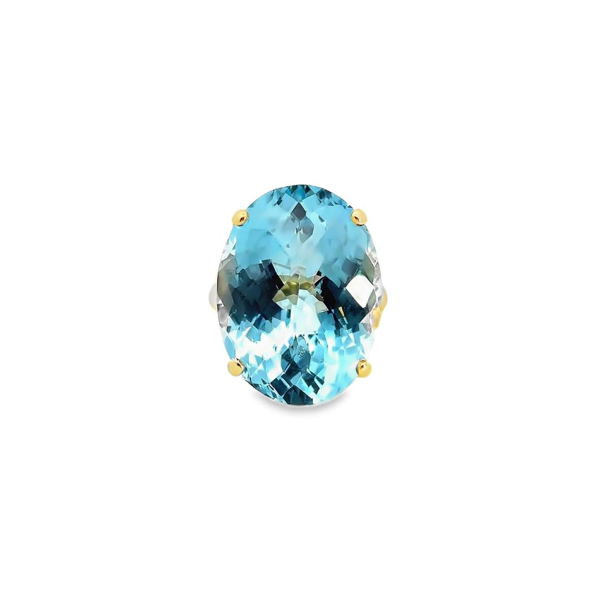 9ct yellow gold ring featuring a 23.70 x 17.75mm oval cut blue topaz in a four-claw setting with engraved shoulders.