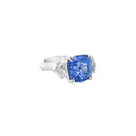 18ct white gold three stone ring featuring an 8.07ct cushion cut blue sapphire with cadillac cut diamond side stones and sapphire-diamond accents in the undercarriage.