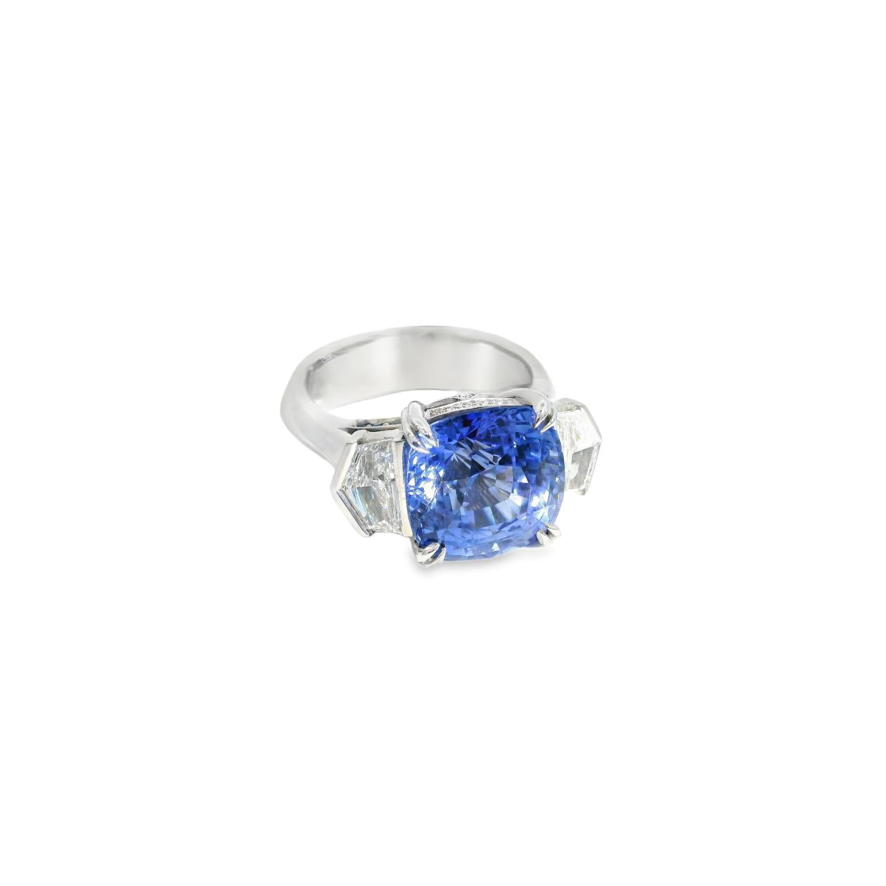 18ct white gold three stone ring featuring an 8.07ct cushion cut blue sapphire with cadillac cut diamond side stones and sapphire-diamond accents in the undercarriage.