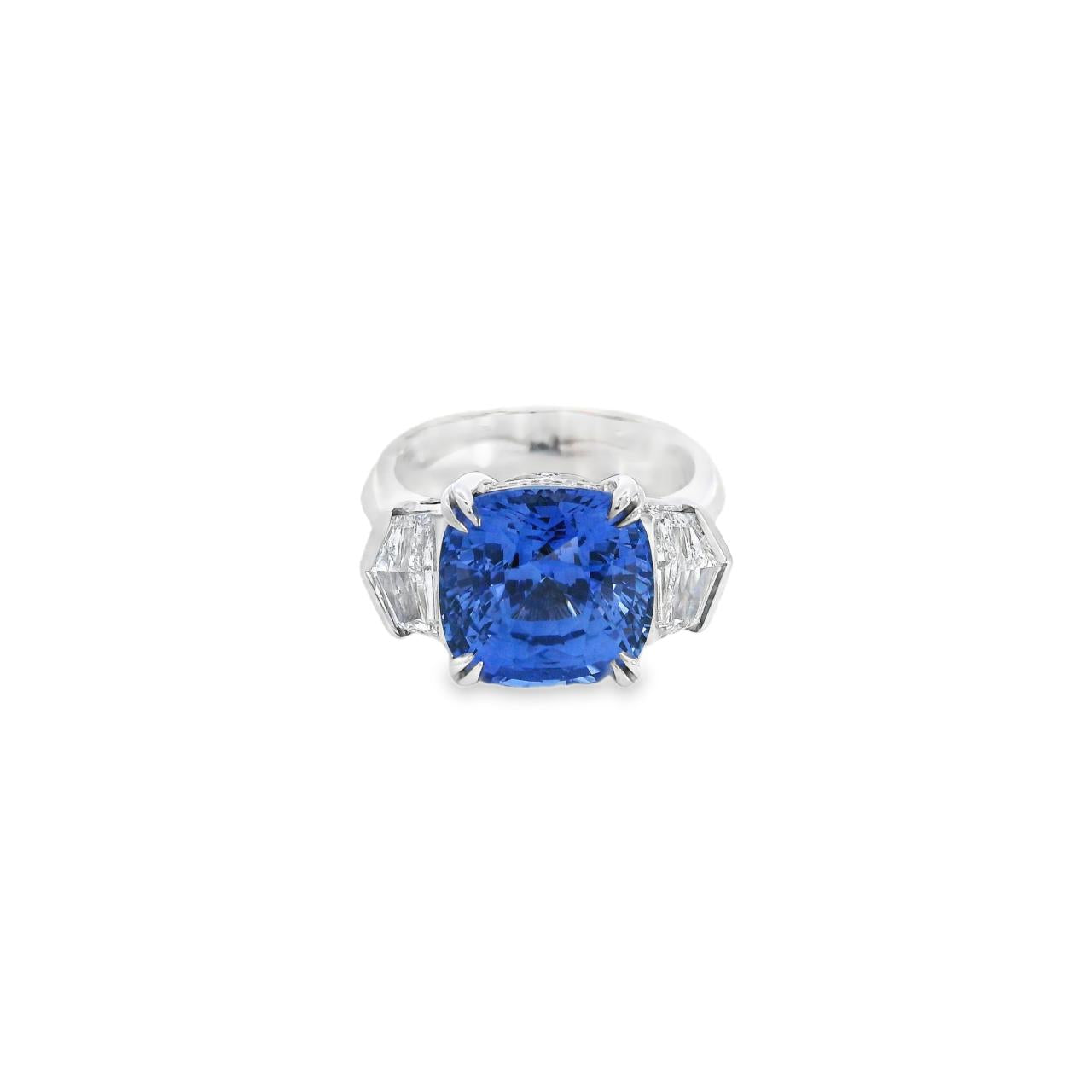 18ct white gold three stone ring featuring an 8.07ct cushion cut blue sapphire with cadillac cut diamond side stones and sapphire-diamond accents in the undercarriage.