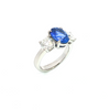 18ct white gold three-stone ring featuring a 2.86ct oval cut Ceylon sapphire with two round brilliant cut diamond side stones.