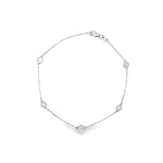 18ct white gold diamond bracelet featuring a fine trace link chain, central circular mini disc with bead-set diamond cluster, bezel-set diamonds along the length, and an adjustable parrot clasp.