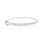 18ct white gold diamond bangle featuring claw-set round brilliant cut diamonds across the top, hinged oval profile with slide catch and safety clasps.