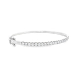 18ct white gold diamond bangle featuring claw-set round brilliant cut diamonds across the top, hinged oval profile with slide catch and safety clasps.