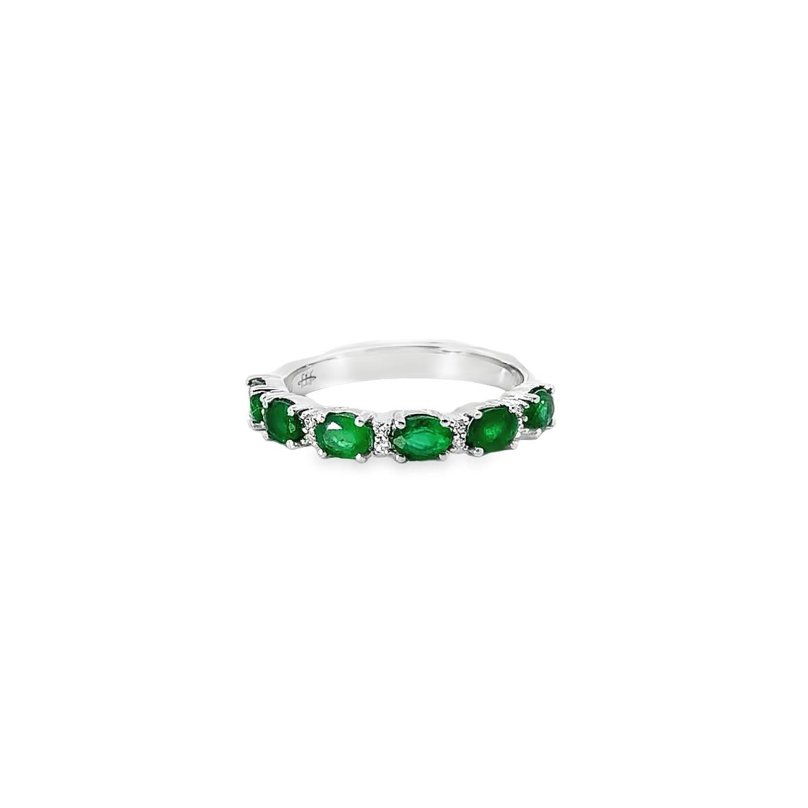 18ct white gold ring featuring alternating claw-set oval-cut emeralds and round brilliant cut diamonds in a horizontal design across the top.