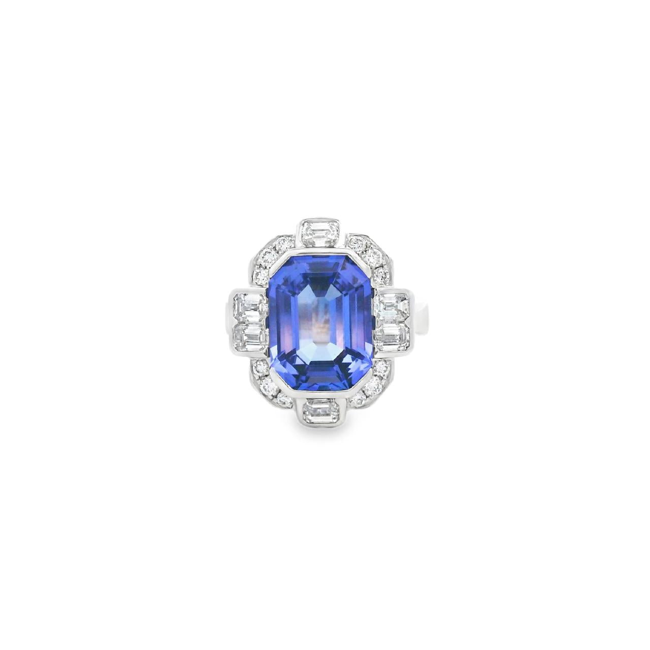 18ct white gold ring featuring a 5.11ct emerald cut tanzanite framed by emerald and round brilliant cut diamonds in a detailed halo setting with upswept shoulders.