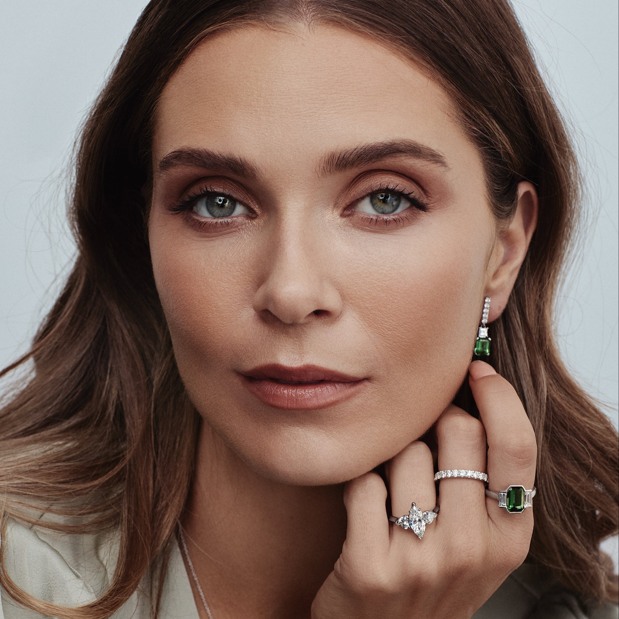 18ct white gold three-stone ring featuring a 2.64ct emerald cut blue-green tourmaline with two baguette cut diamonds in a continuous semi-bezel setting.