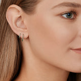 18ct white gold huggie earrings featuring claw-set emeralds along the front and back, medium size with 11mm inside diameter and hinged fittings.