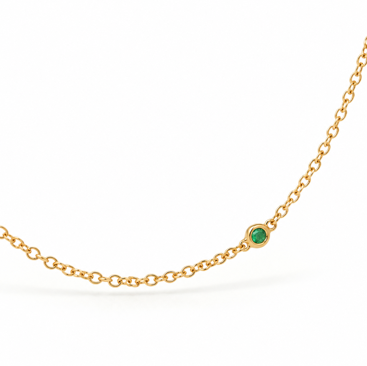 18ct yellow gold emerald station necklet featuring seven round-cut green emeralds in individual bezel settings along a fine 42cm trace chain.