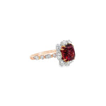 18ct rose gold ring featuring a 4.55ct cushion Malaya garnet with alternating marquise and round diamond clusters surrounding the centre stone and along the shoulders.