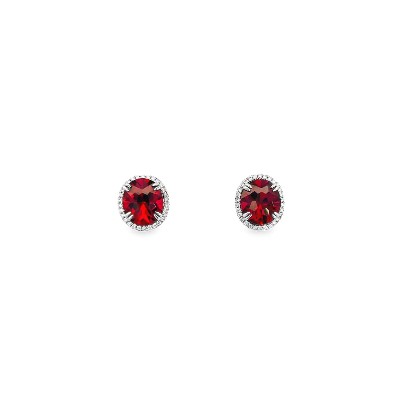 18ct white gold stud earrings featuring oval-cut garnets surrounded by a halo of round brilliant cut diamonds, with post and butterfly fittings.
