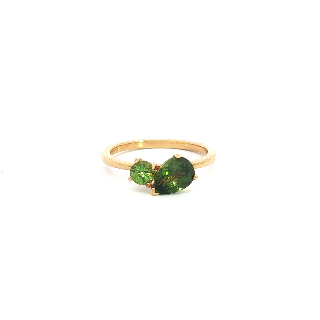 9ct yellow gold “Toi et Moi” ring featuring a 1.22ct pear cut and 0.32ct round green sapphire in angled claw settings with post and bezel collets.