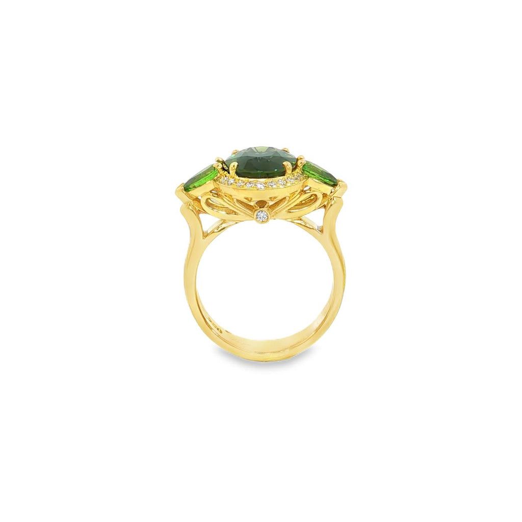 18ct yellow gold ring featuring oval green sapphire, tsavorite garnets, and diamond halo design with intricate undercarriage detail.