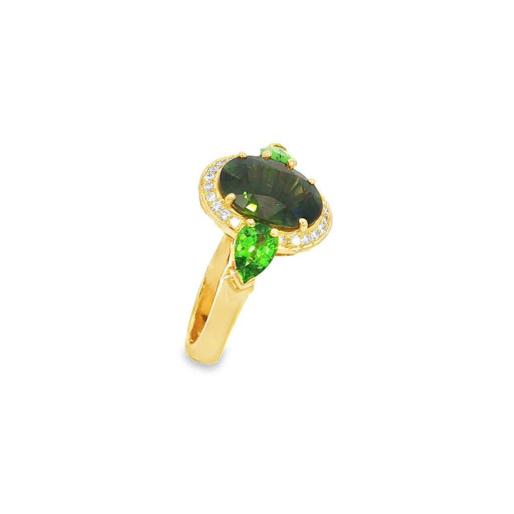 18ct yellow gold ring featuring oval green sapphire, tsavorite garnets, and diamond halo design with intricate undercarriage detail.