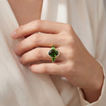 18ct yellow gold ring featuring oval green sapphire, tsavorite garnets, and diamond halo design with intricate undercarriage detail.