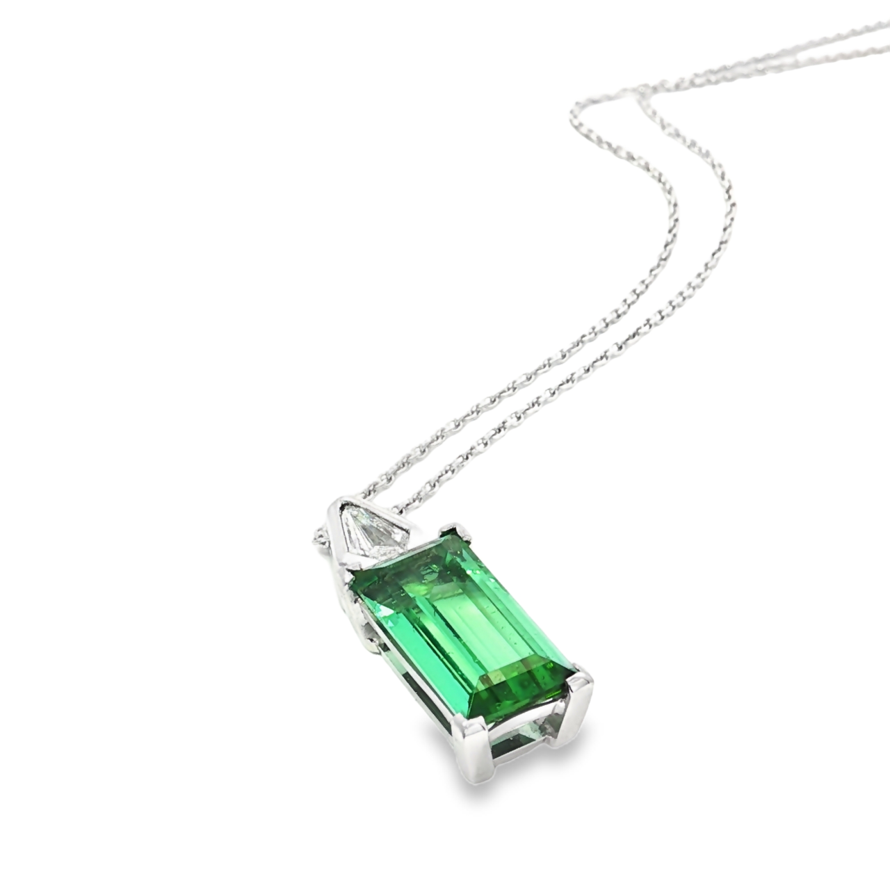 18ct white gold pendant featuring a 4.24ct rectangular cut green tourmaline and bezel-set shield diamond on a fine trace link chain.
