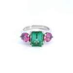 Platinum three-stone ring featuring a 2.68ct emerald cut green tourmaline with two round cut pink spinels in tiered claw settings.