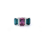18ct white gold ring featuring a 2.11ct emerald cut purple-pink Malaia garnet with two greenish-blue tourmalines and diamond-set tiered claw and bar details.