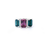 18ct white gold ring featuring a 2.11ct emerald cut purple-pink Malaia garnet with two greenish-blue tourmalines and diamond-set tiered claw and bar details.