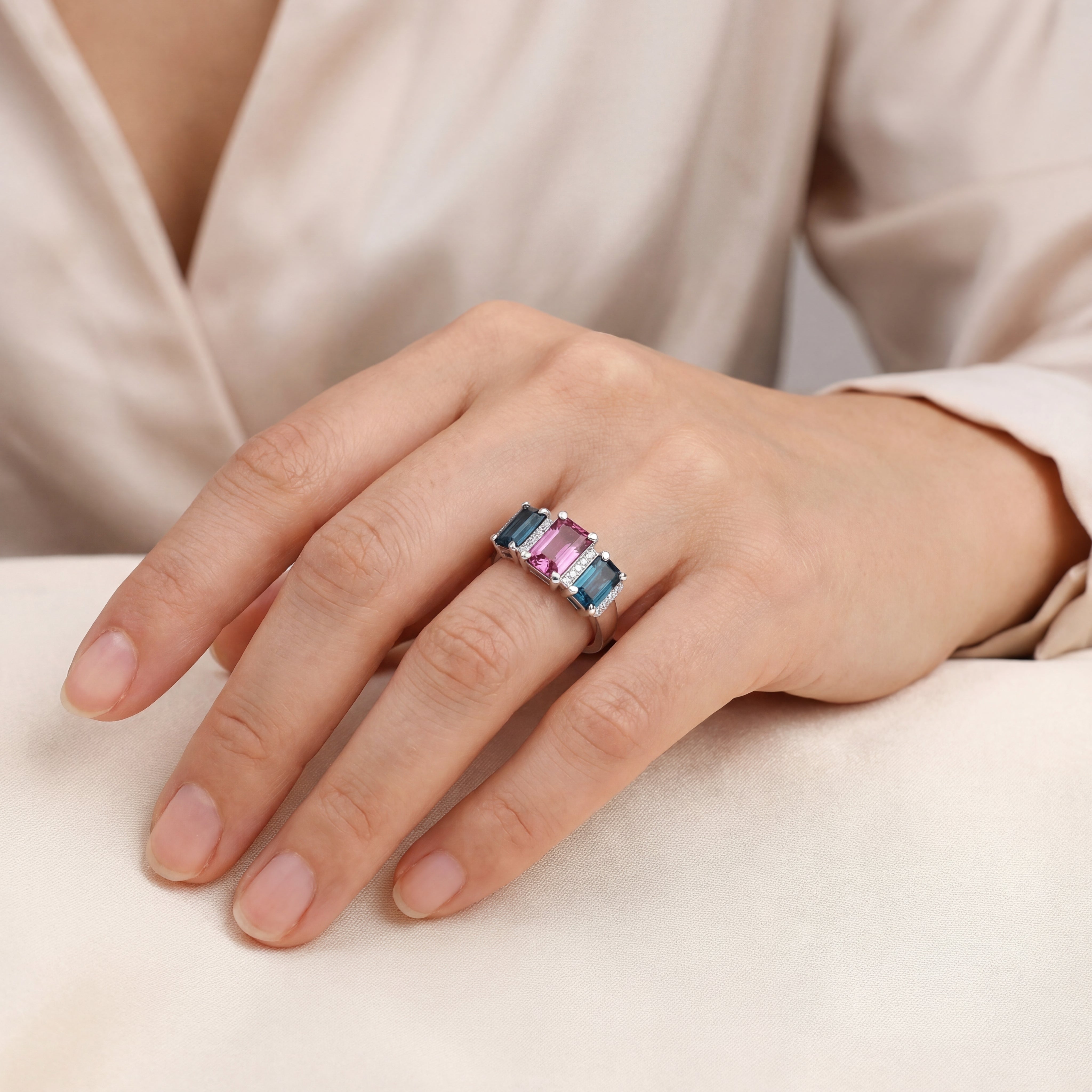 18ct white gold ring featuring a 2.11ct emerald cut purple-pink Malaia garnet with two greenish-blue tourmalines and diamond-set tiered claw and bar details.
