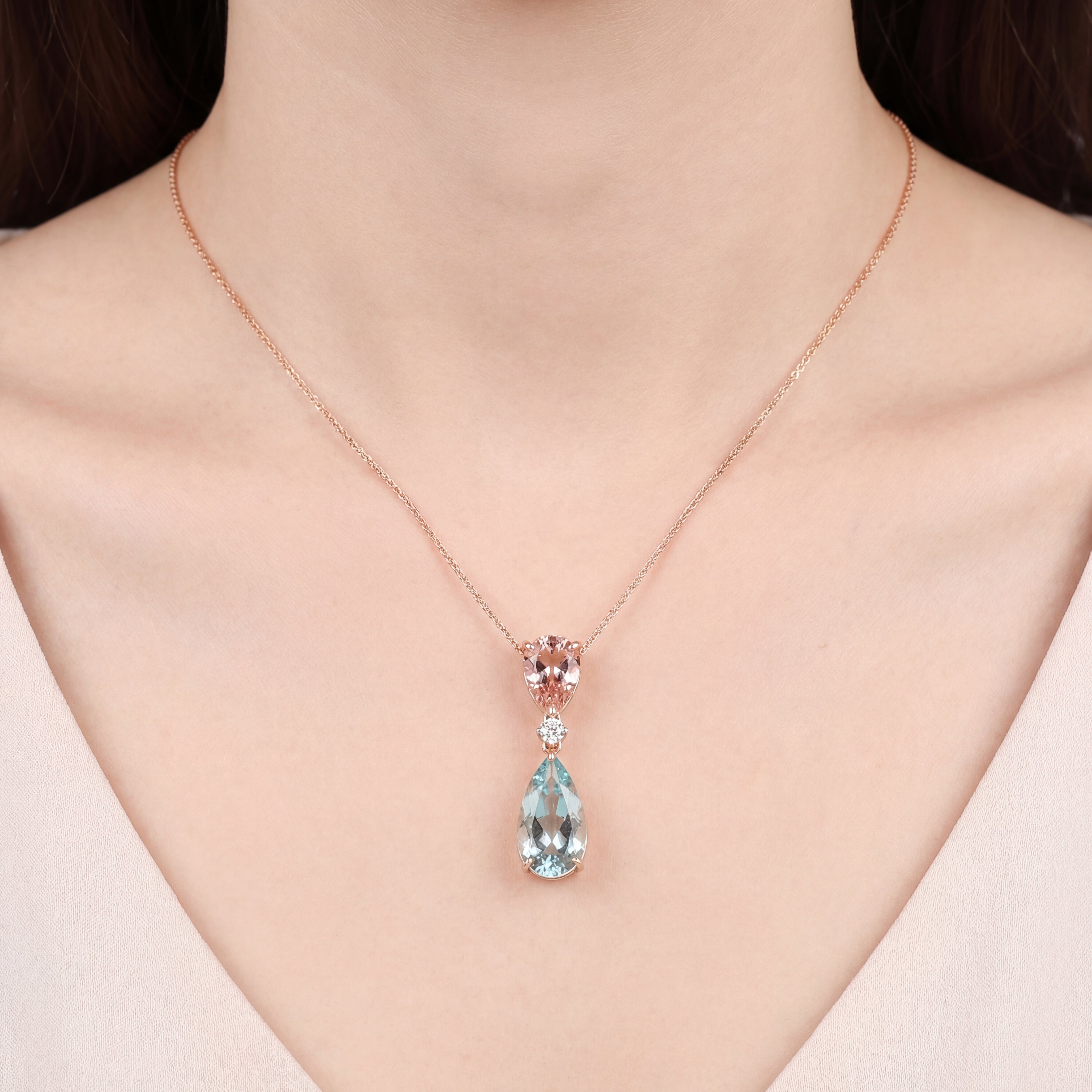 18ct rose and white gold pendant featuring pear-cut morganite and aquamarine with a central diamond accent and concealed pendant runner.