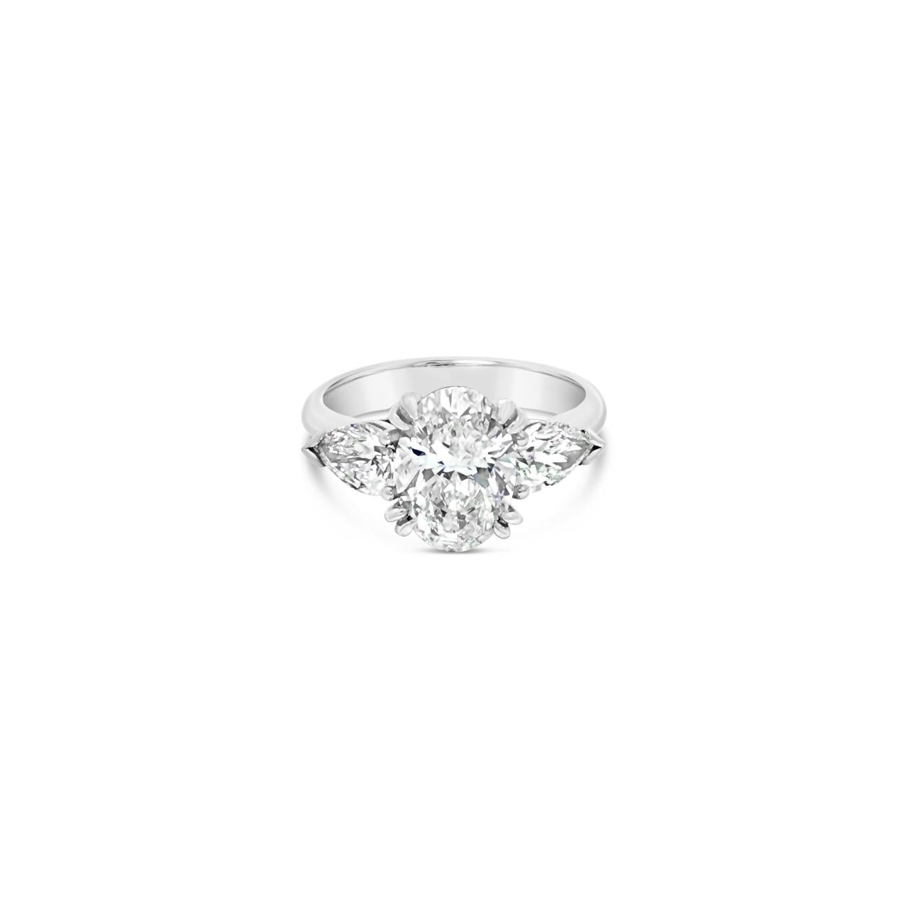 18ct white gold three stone diamond ring featuring a 2.17ct oval centre diamond with pear cut diamond side stones in tiered cap-and-claw settings.