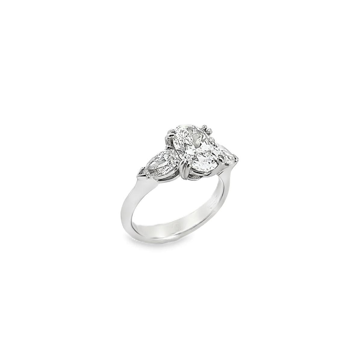 18ct white gold three stone diamond ring featuring a 2.17ct oval centre diamond with pear cut diamond side stones in tiered cap-and-claw settings.