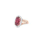18ct rose and white gold ring featuring a 9.25ct oval pink tourmaline surrounded by a halo of diamonds, with rubies bead set into the undercarriage and split claw shoulders.