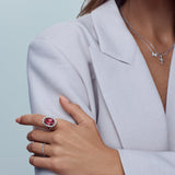 18ct rose and white gold ring featuring a 9.25ct oval pink tourmaline surrounded by a halo of diamonds, with rubies bead set into the undercarriage and split claw shoulders.