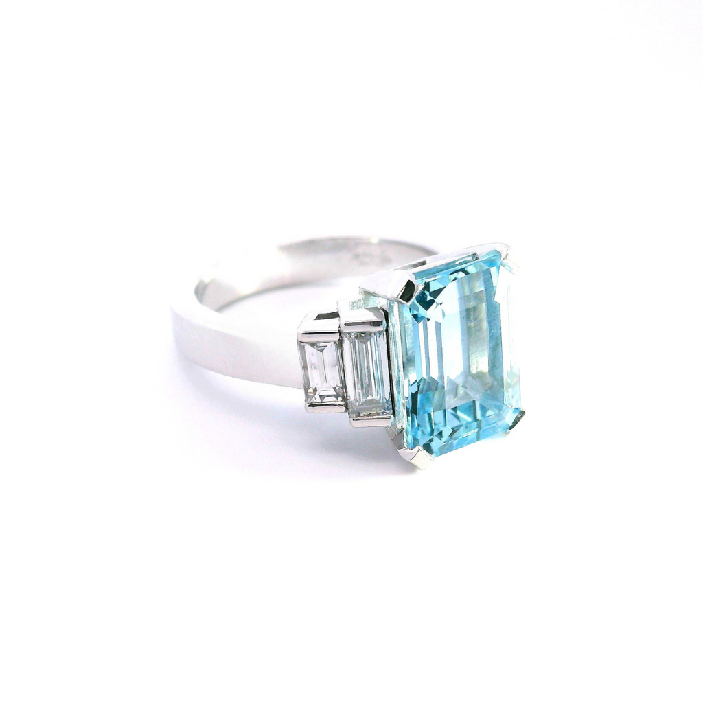 Platinum ring with emerald-cut aquamarine and stepped baguette diamond shoulders.
