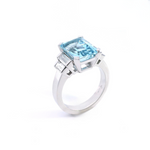 Platinum ring with emerald-cut aquamarine and stepped baguette diamond shoulders.