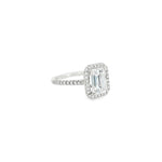 Platinum emerald cut diamond ring with halo and diamond-set shoulders.