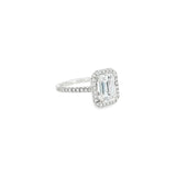 Platinum emerald cut diamond ring with halo and diamond-set shoulders.