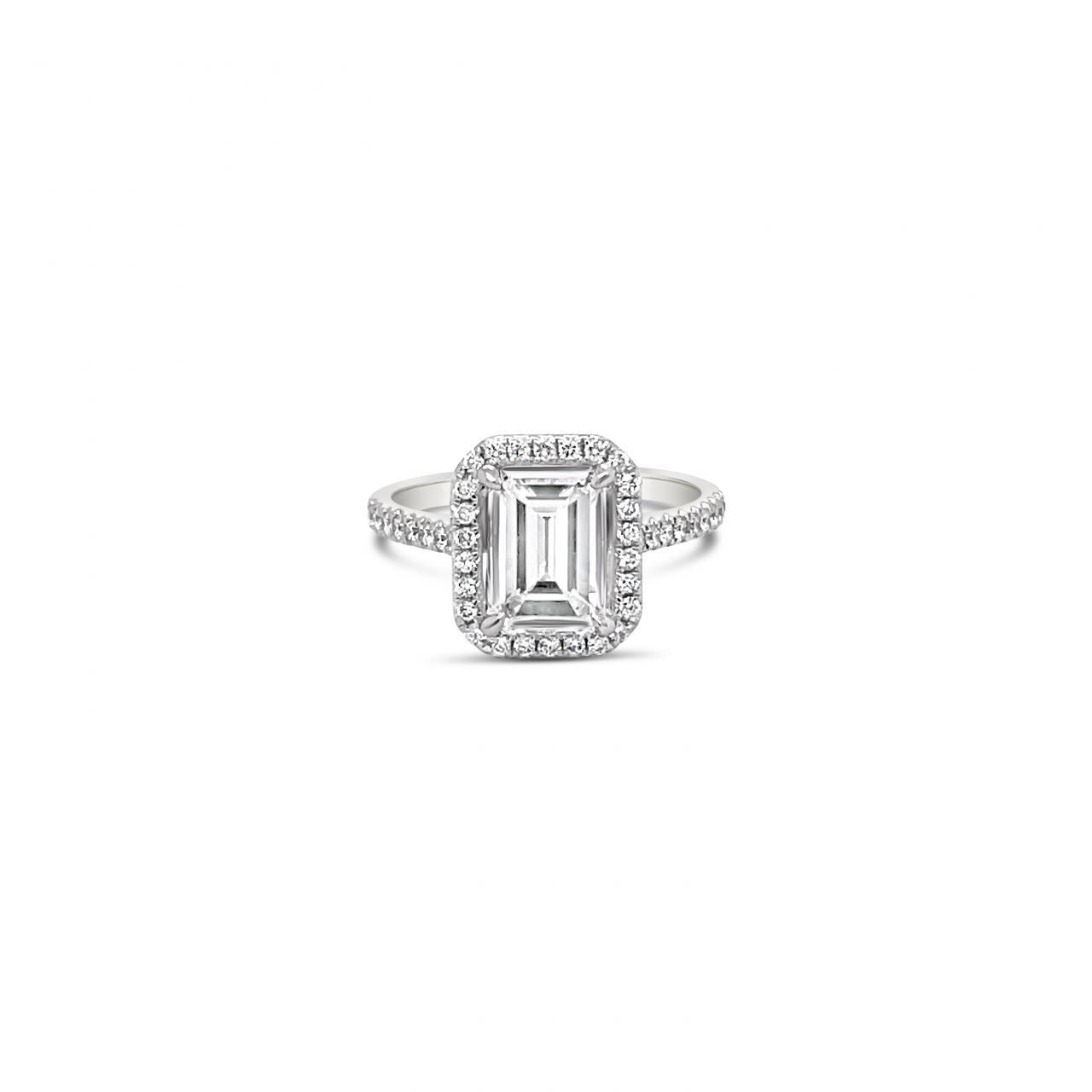 Platinum emerald cut diamond ring with halo and diamond-set shoulders.