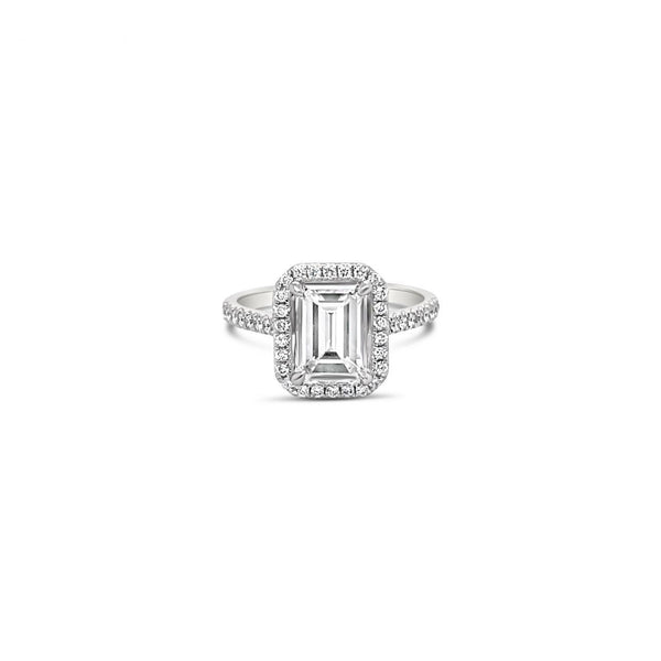 Platinum emerald cut diamond ring with halo and diamond-set shoulders.