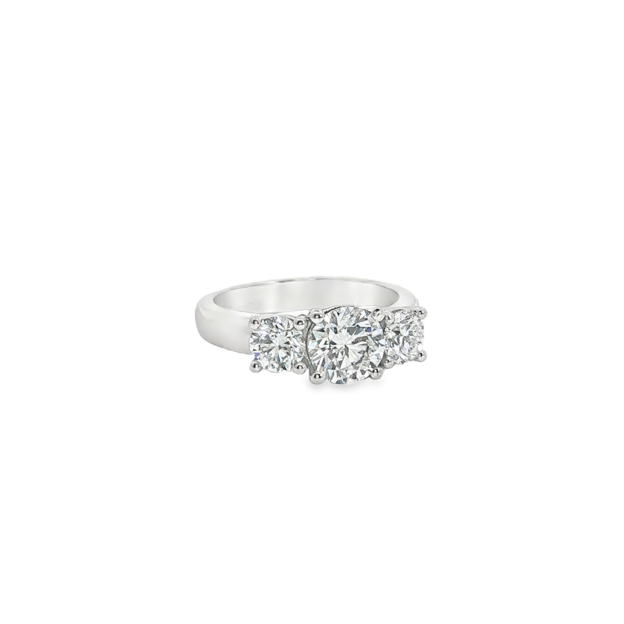 Platinum three-stone diamond ring with tiered round brilliant cut settings.