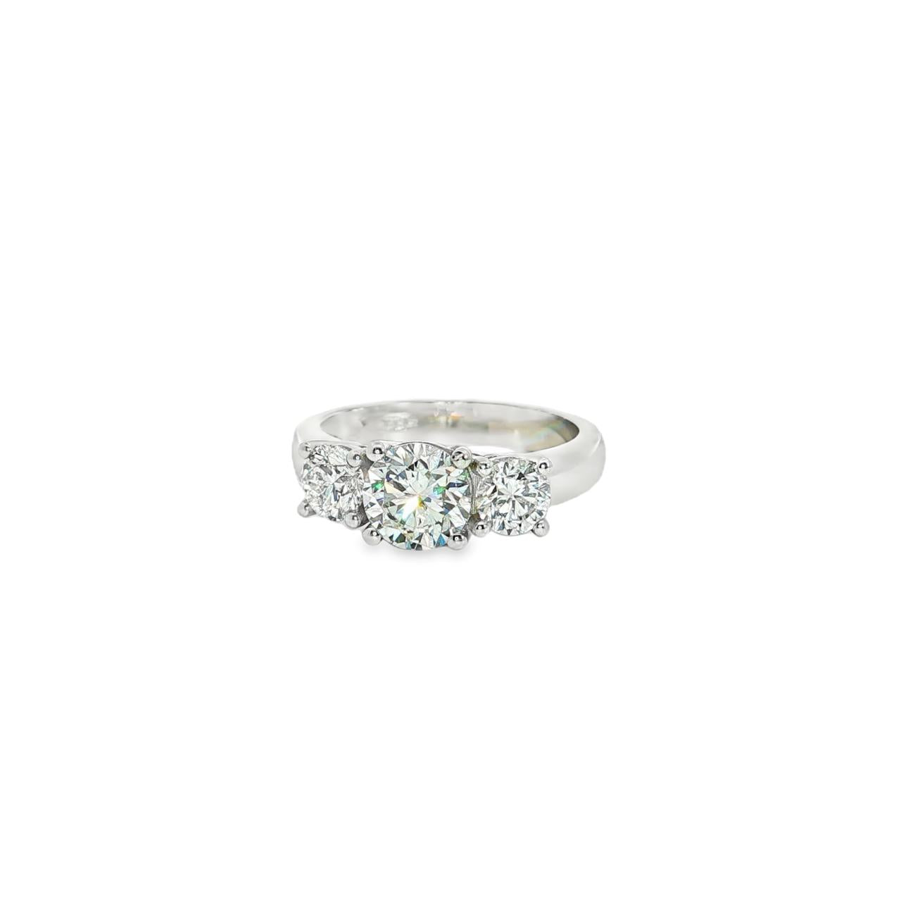 Platinum three-stone diamond ring with tiered round brilliant cut settings.