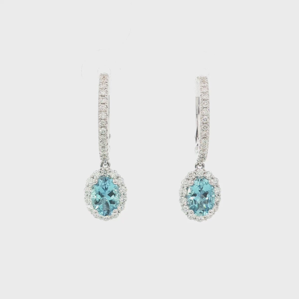 18ct white gold aquamarine and diamond drop earrings with oval blue gemstones and diamond halo