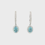 18ct white gold aquamarine and diamond drop earrings with oval blue gemstones and diamond halo
